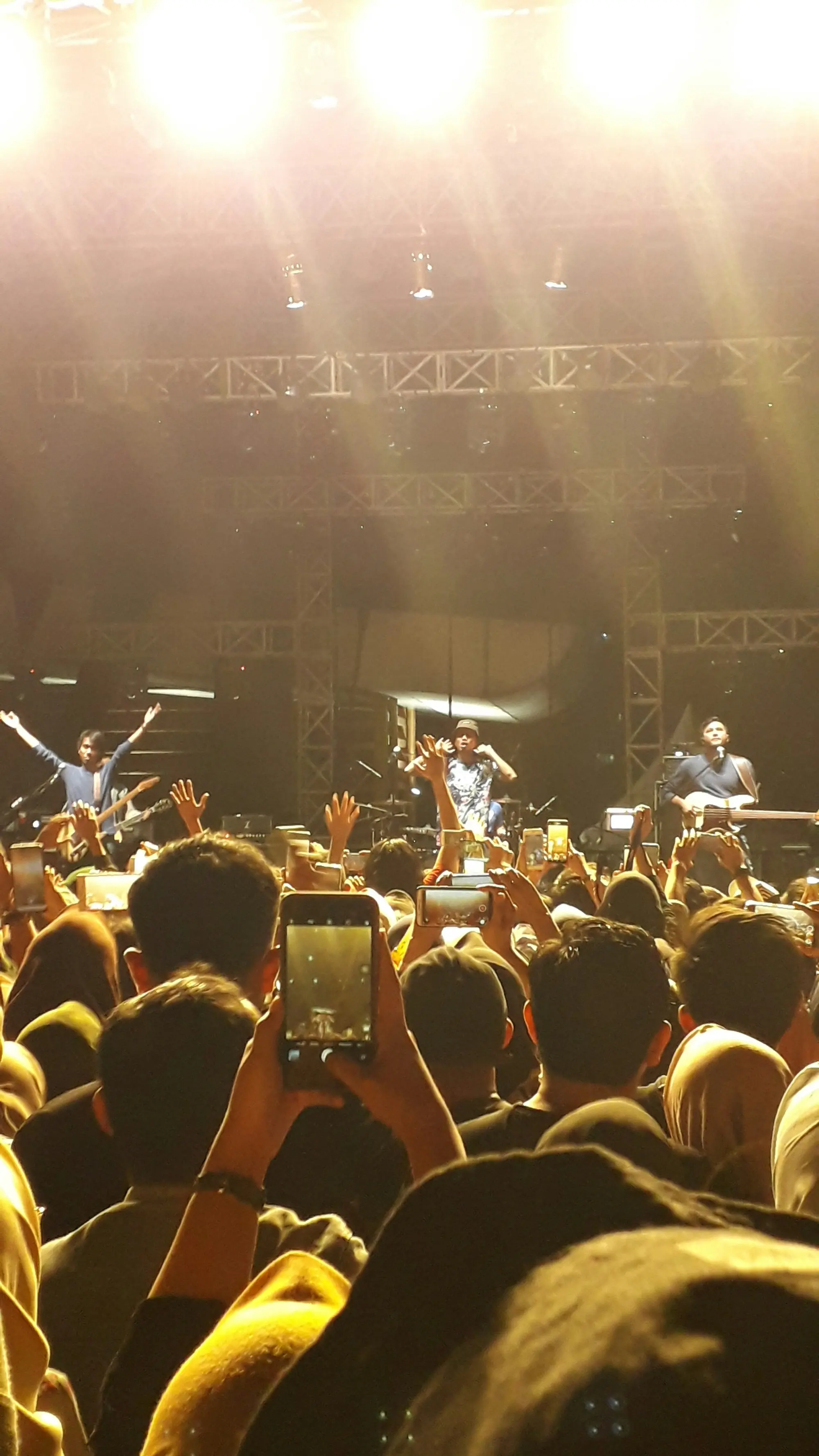 A band on stage, phones raised in the crowd